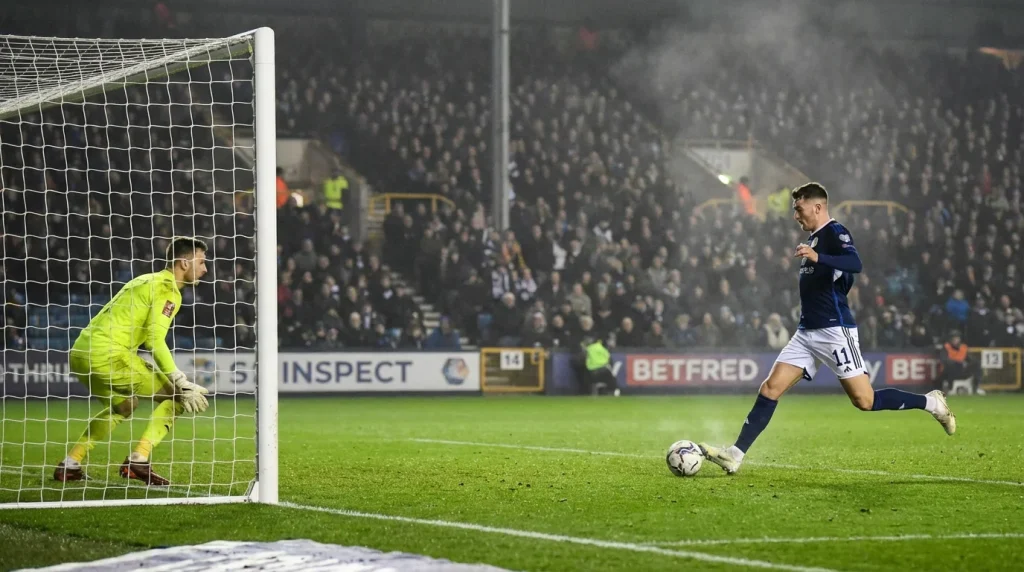 Voetbalspeler die een schot op doel lost in een vol stadion tijdens een spannend moment